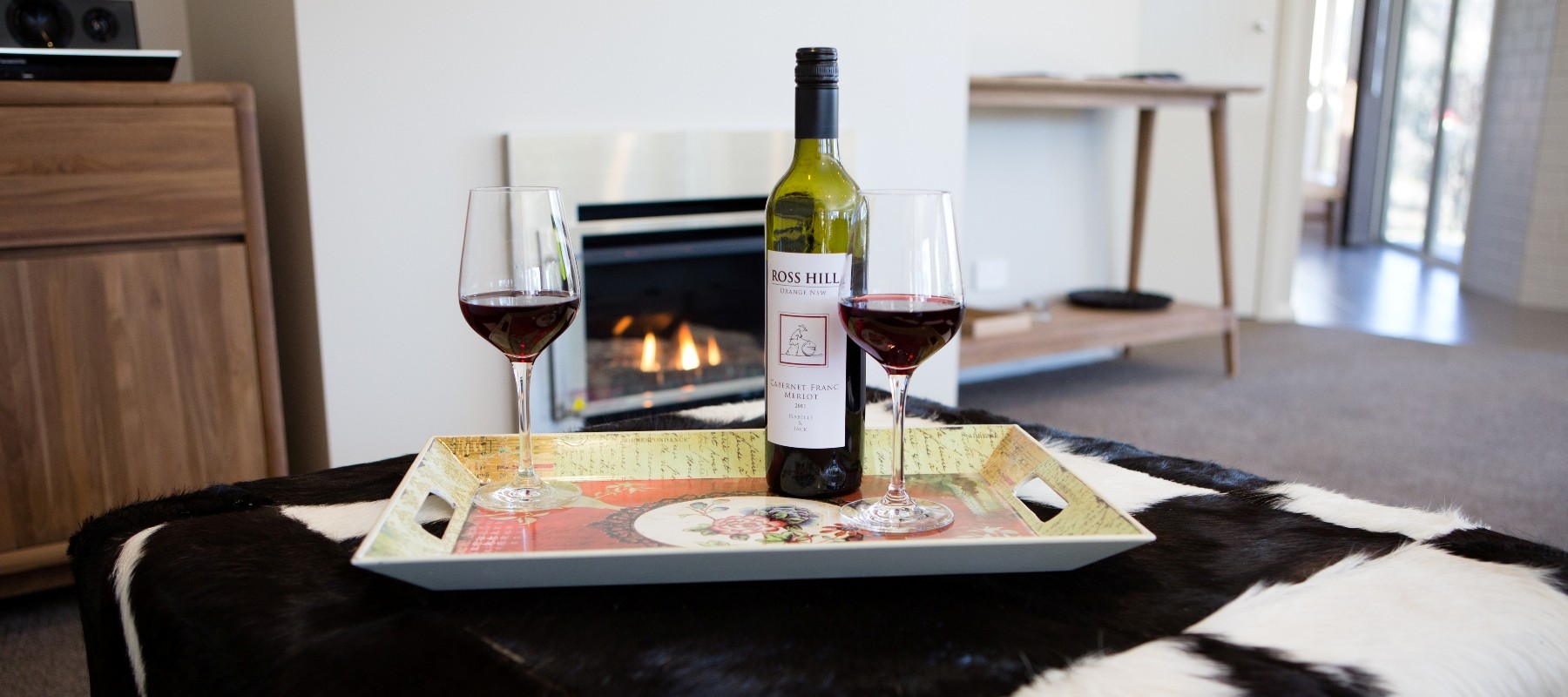 Two glasses and a bottle of wine in front of a fireplace
